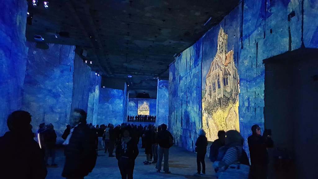 Visit of the Carrières des Lumières, semi darkness with Van Gogh painting on walls.